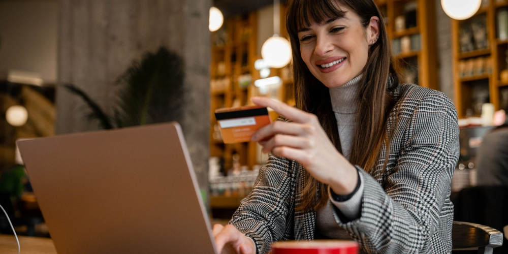 young business woman in a coffee shop using credit card with laptop