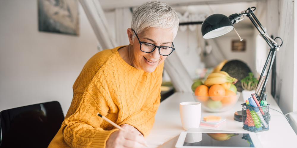 Stylish older woman at desk, short gray hair, orange sweater