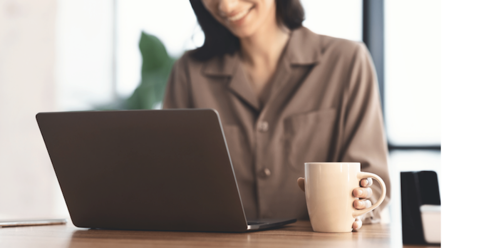 smiling woman with coffee cup and computer