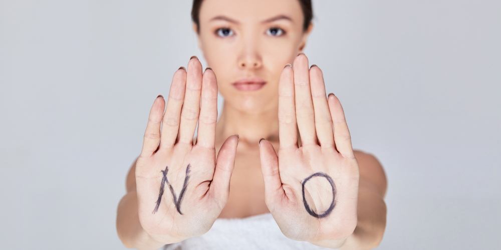 woman holding up hands with NO written in marker