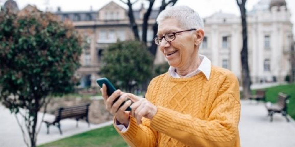 elderly woman in orange sweater outside texting