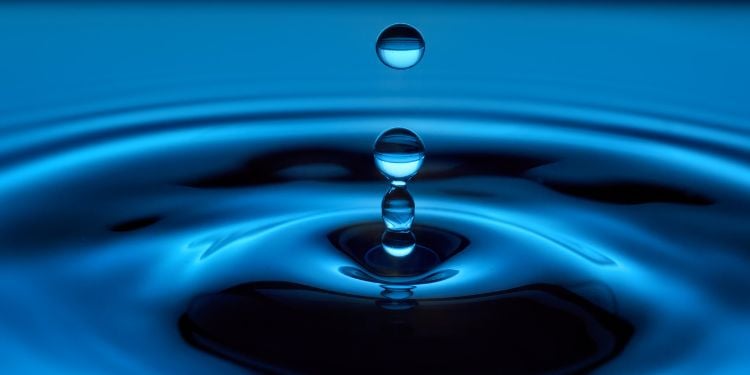 droplets falling into deep blue water, with ripples spreading out