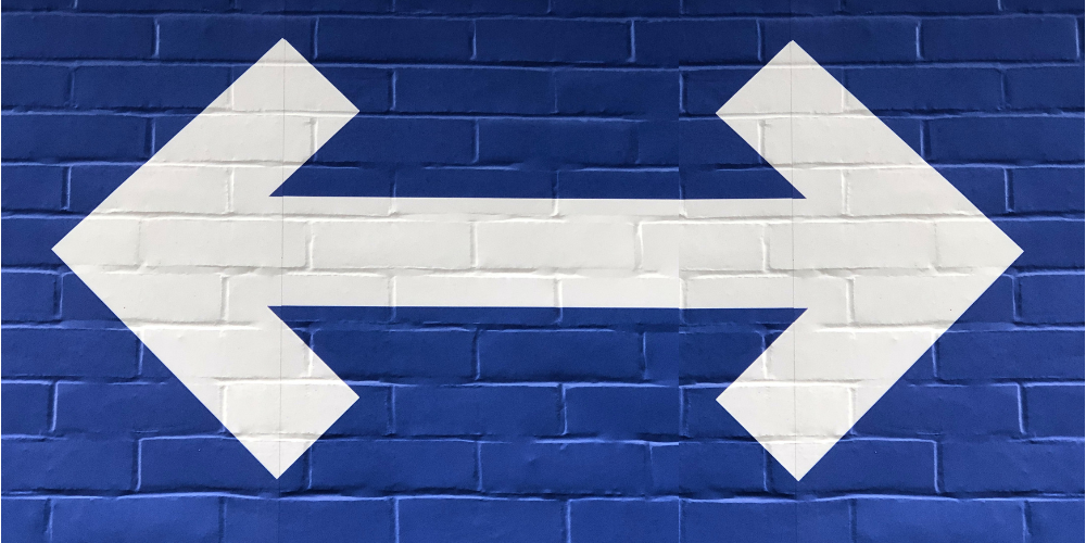white 2-way arrow with dark blue brick background